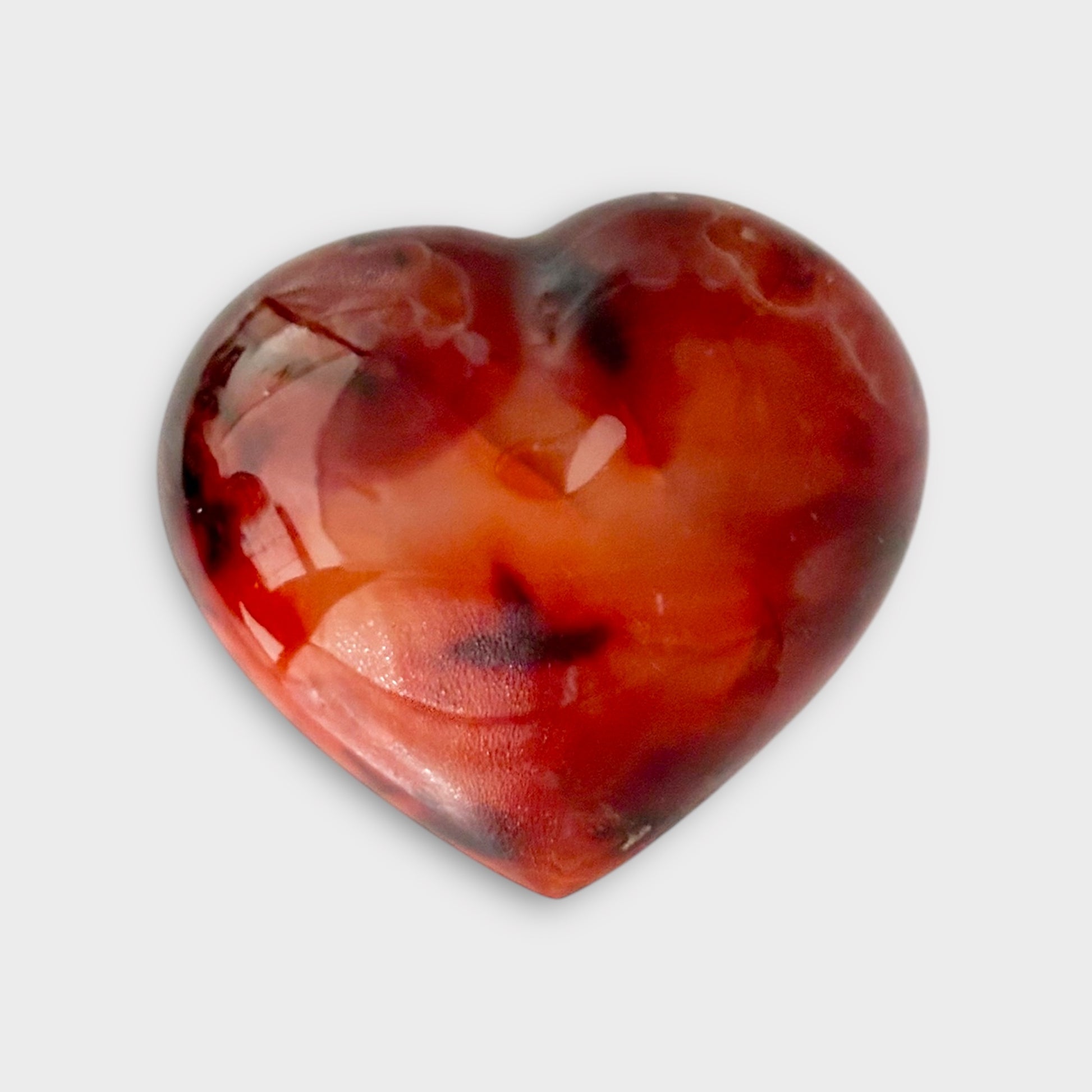 A Carnelian Heart displayed on a white background, showcasing its bold orange tones and polished finish.