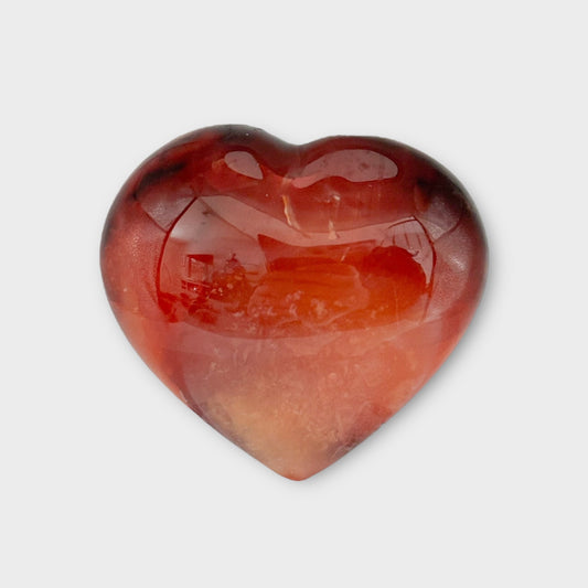 Close-up of a Carnelian Heart on a white background, emphasizing its natural stone patterns and fiery energy.