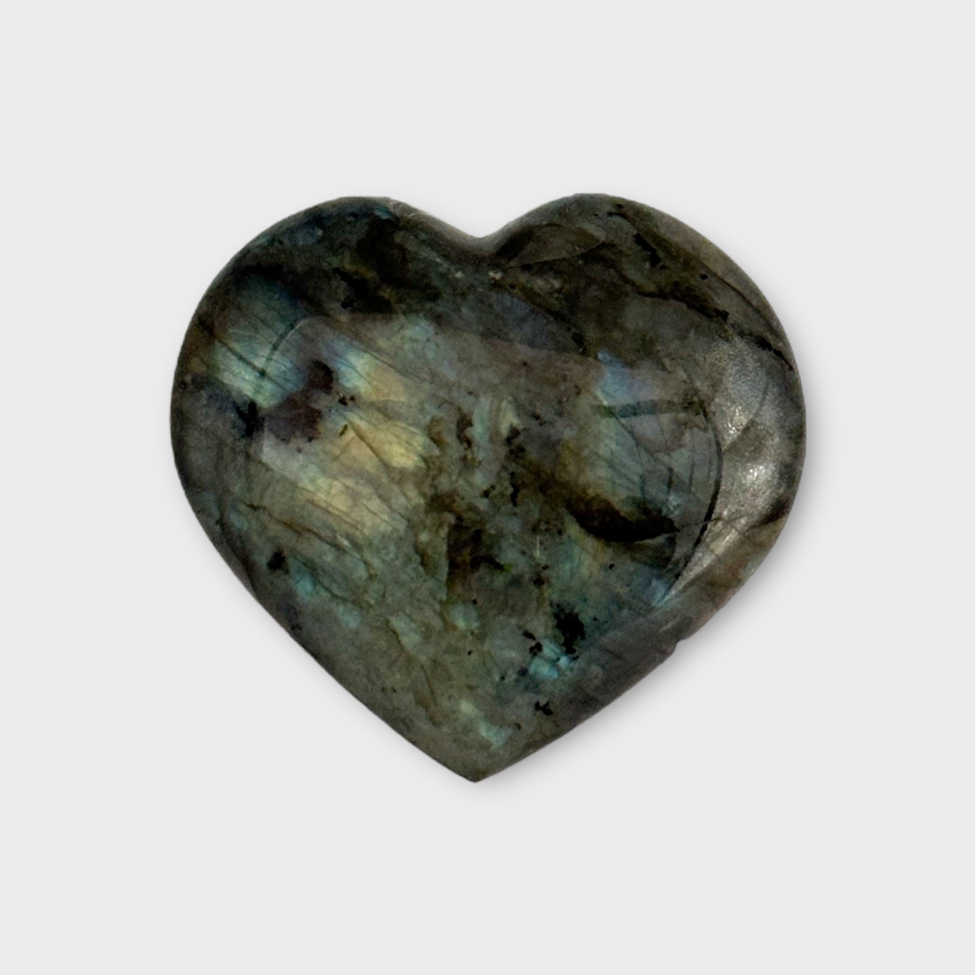 A Labradorite Heart placed on a white background, highlighting its polished surface and unique flashes of color.