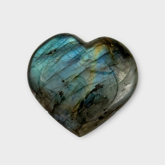 Close-up of a Labradorite Heart on a plain white background, emphasizing its shimmering blue and green tones.