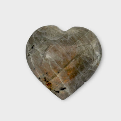 Detailed shot of a Labradorite Heart on a white background, showing its vibrant, glowing streaks of Orange and blue.