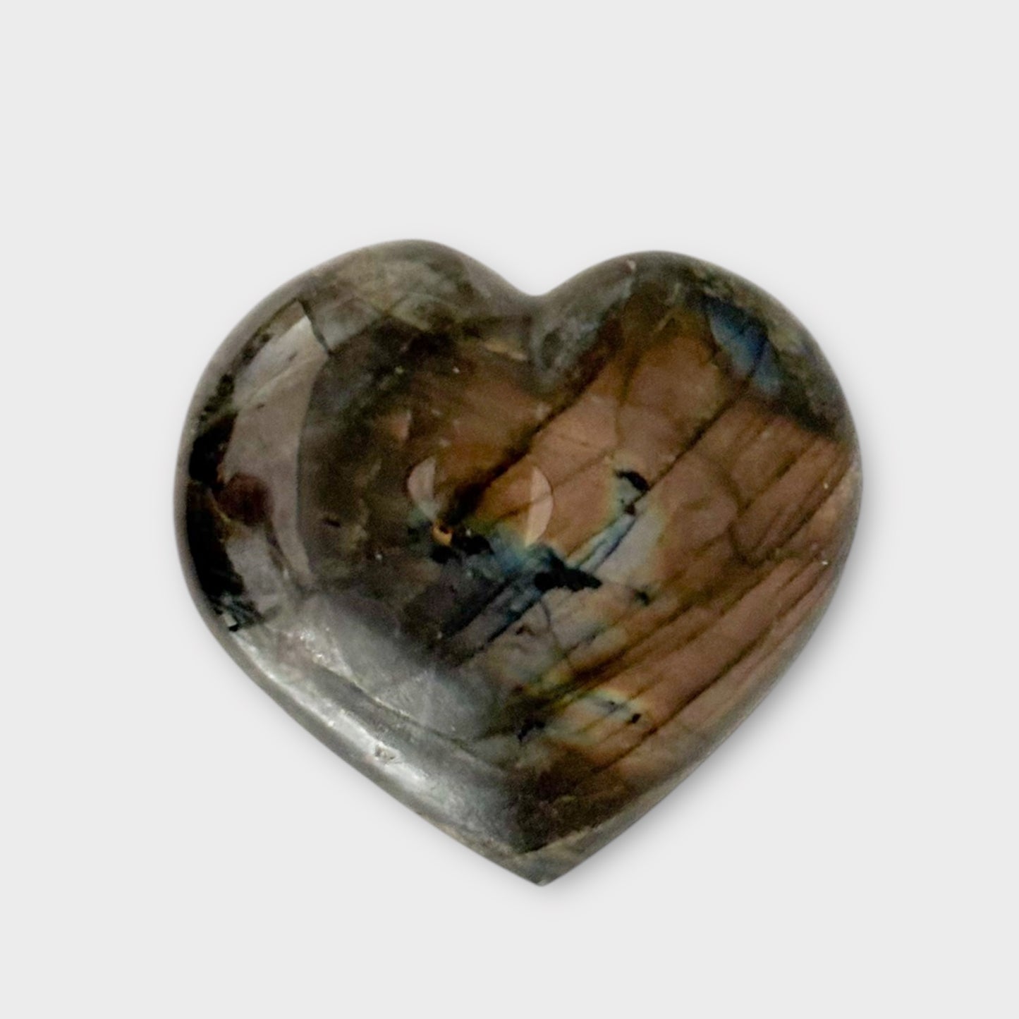 Close-up of the shimmering details on a Labradorite Heart placed on a plain white background.