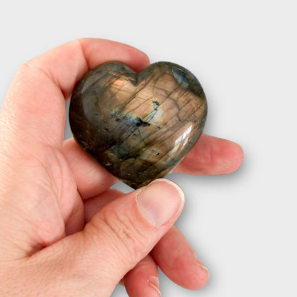 Close-up of a Labradorite Heart resting in a hand, emphasizing its heart shape and shimmering surface.