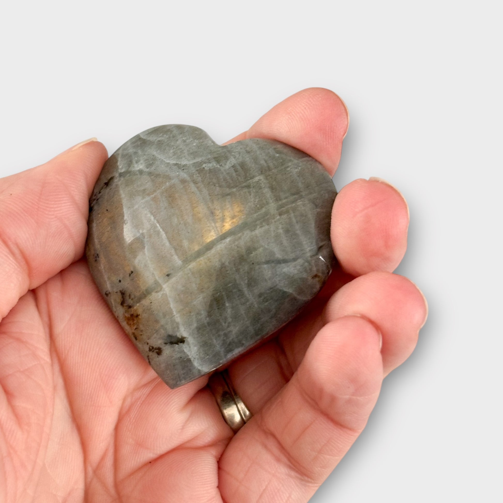 A polished Labradorite Heart in a hand, showcasing its glowing iridescence and smooth texture.