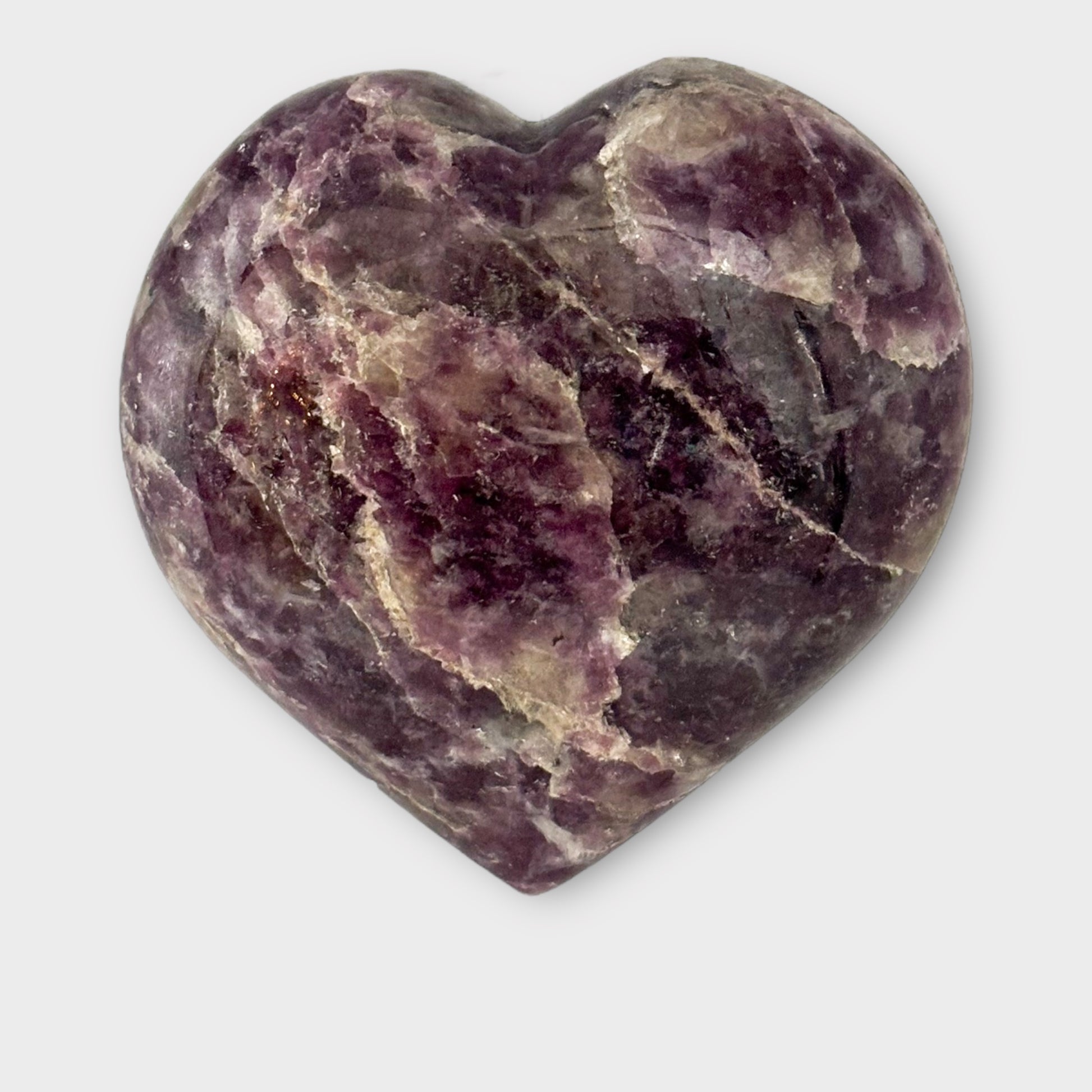 A Lepidolite Heart placed on a plain white background, photographed from above to showcase its polished surface and heart shape.