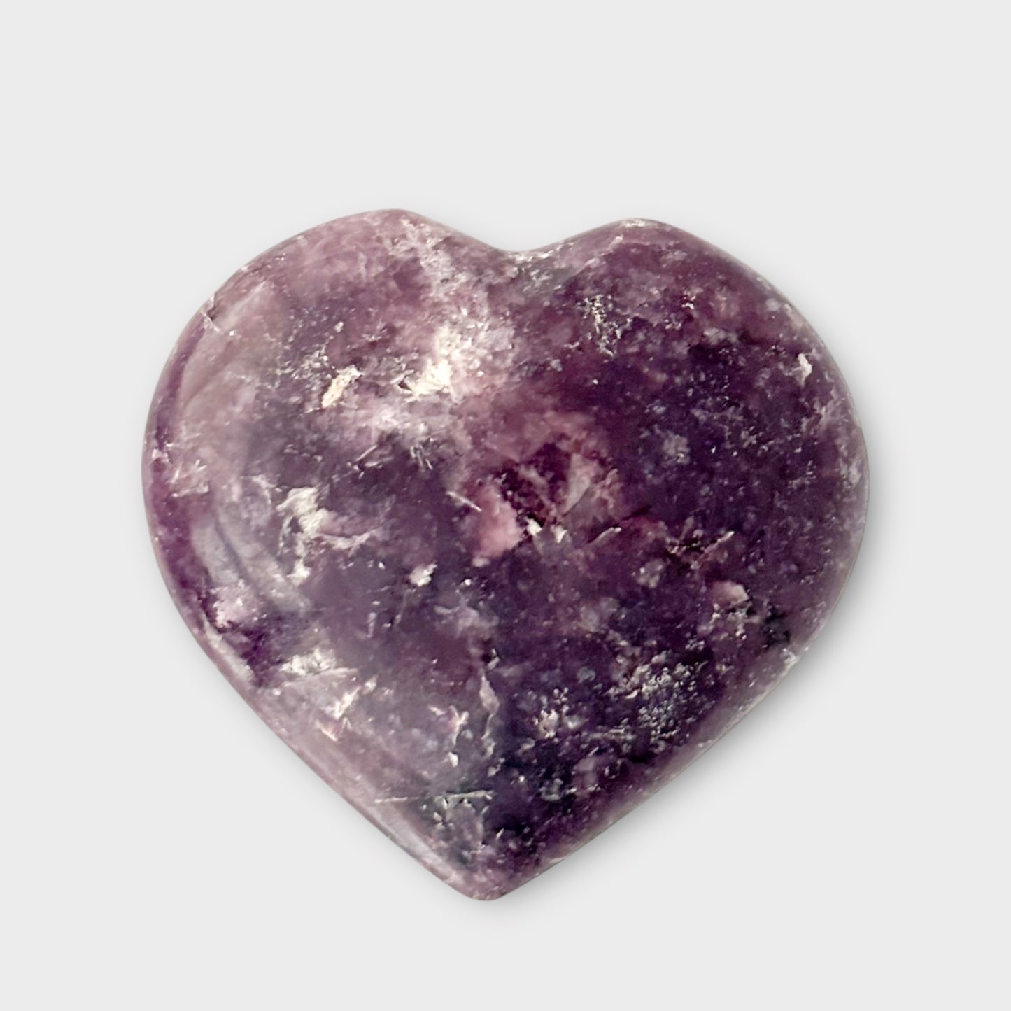 A Lepidolite Heart sitting on a plain white background, showing its glossy finish and soothing lavender color.