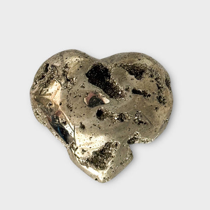 A polished Pyrite Heart displayed on a white background, emphasizing its smooth metallic surface and golden tones.