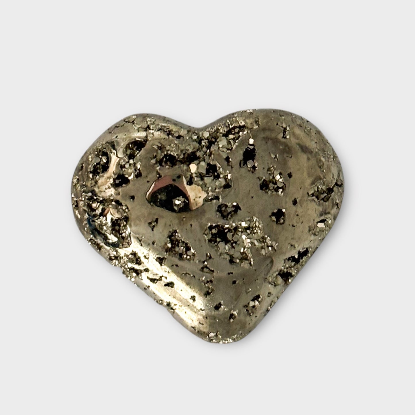 Side view of a Pyrite Heart on a plain white background, showcasing its curved edges and natural metallic luster.