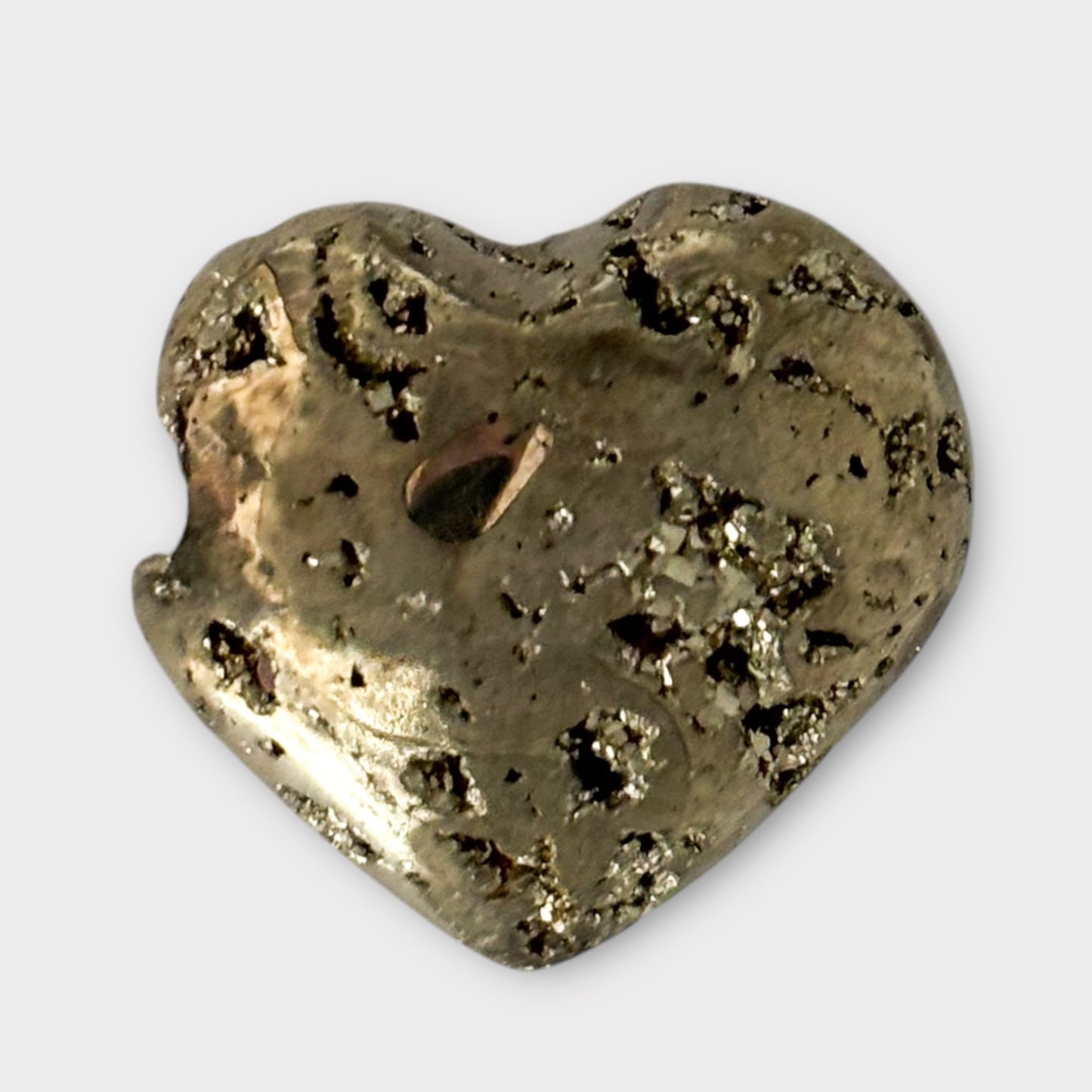 A top-down view of a Pyrite Heart on a white background, capturing its symmetrical heart shape and glittering surface.