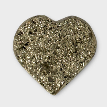 Close-up of a Pyrite Heart’s textured surface on a white background, emphasizing its natural metallic shimmer.