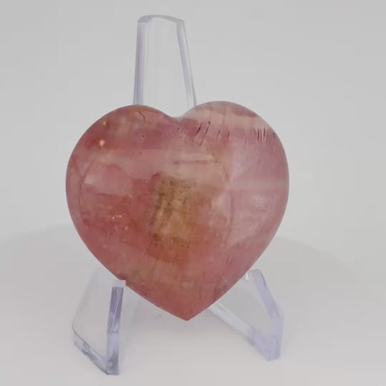 A rotating video of a polished pink Polychrome Jasper Heart, showcasing its smooth surface, soft pink tones, and natural patterns.